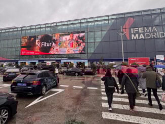 Fachada de IFEMA Madrid durante FITUR 2025 con asistentes bajo la lluvia ingresando al evento