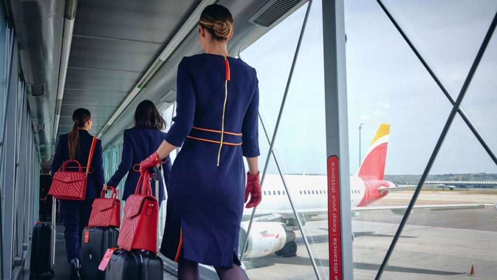 Tripulación de cabina de Iberia caminando hacia un avión estacionado en el aeropuerto, simbolizando los nuevos vuelos económicos disponibles en 2025