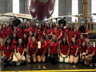 Chicas participantes del programa Quiero Ser de Iberia frente a un avión en el hangar de mantenimiento
