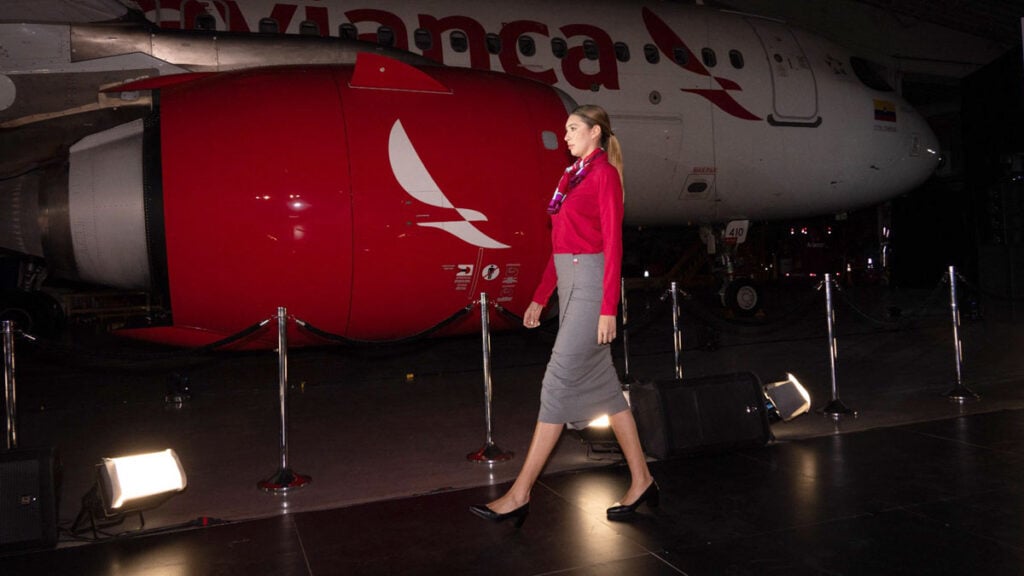 Tripulante de Avianca luce los nuevos uniformes diseñados por Juanjo Oliva frente a un avión de la aerolínea