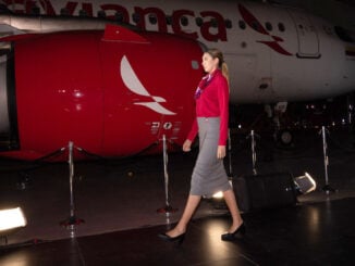Tripulante de Avianca luce los nuevos uniformes diseñados por Juanjo Oliva frente a un avión de la aerolínea