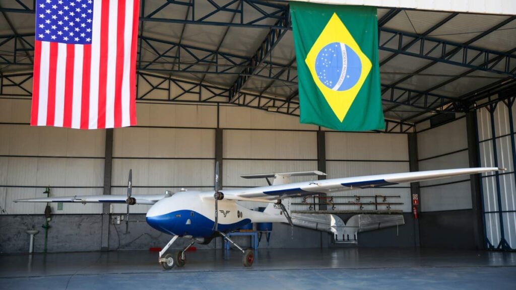Avión autónomo agrícola Pelican 2 de Pyka en hangar con banderas de Estados Unidos y Brasil