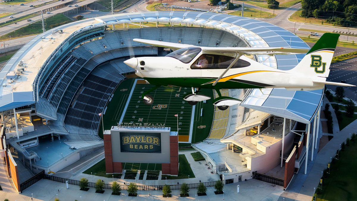 Avión Tecnam P2008 con colores de Universal Flight Concepts sobrevolando el estadio McLane de Baylor University en Waco, Texas.