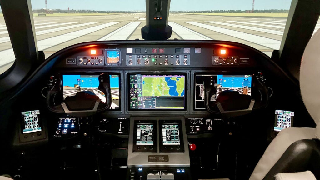 Interior de la cabina del simulador de vuelo completo (FFS) del Cessna Citation Ascend operado por TRU Simulation, mostrando los paneles de aviónica y la proyección visual de la pista