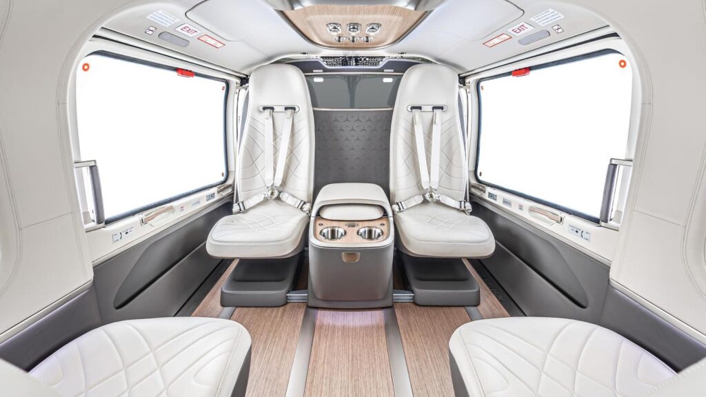 Interior de la cabina del helicóptero Airbus ACH145 Mercedes-Benz Edition con asientos de cuero blanco y acabados en madera.