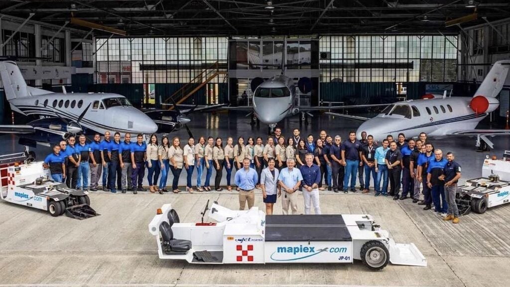El equipo de Mapiex International posando frente a su hangar en Panamá con aeronaves ejecutivas y vehículos de remolque de alta tecnología