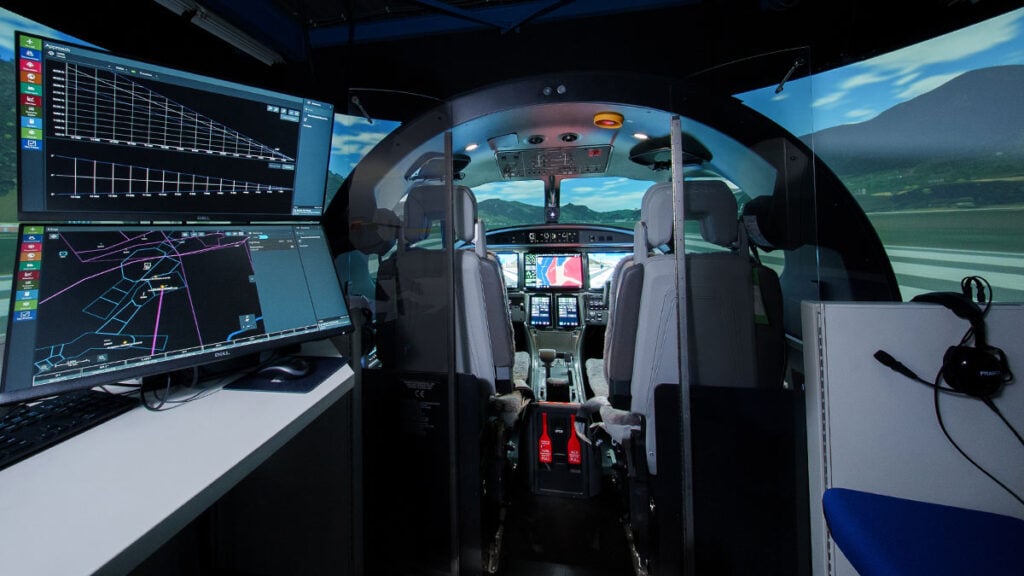 Vista interior de la cabina del simulador de vuelo del Pilatus PC-12 PRO y la estación del instructor con pantallas de control de fallas.