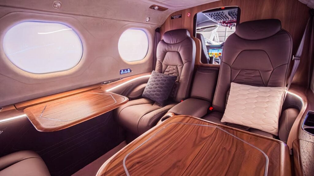 Interior del Tecnam P2012 VIP que destaca los servicios para el ejecutivo moderno: integración de Starlink para internet satelital, cargadores USB-C integrados en los paneles laterales y las mesas eléctricas desplegables para estaciones de trabajo