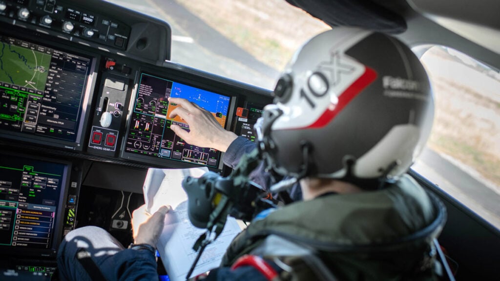Piloto de pruebas de Dassault con casco táctico operando las pantallas táctiles de la aviónica avanzada dentro de la cabina del Falcon 10X durante el vuelo inaugural.