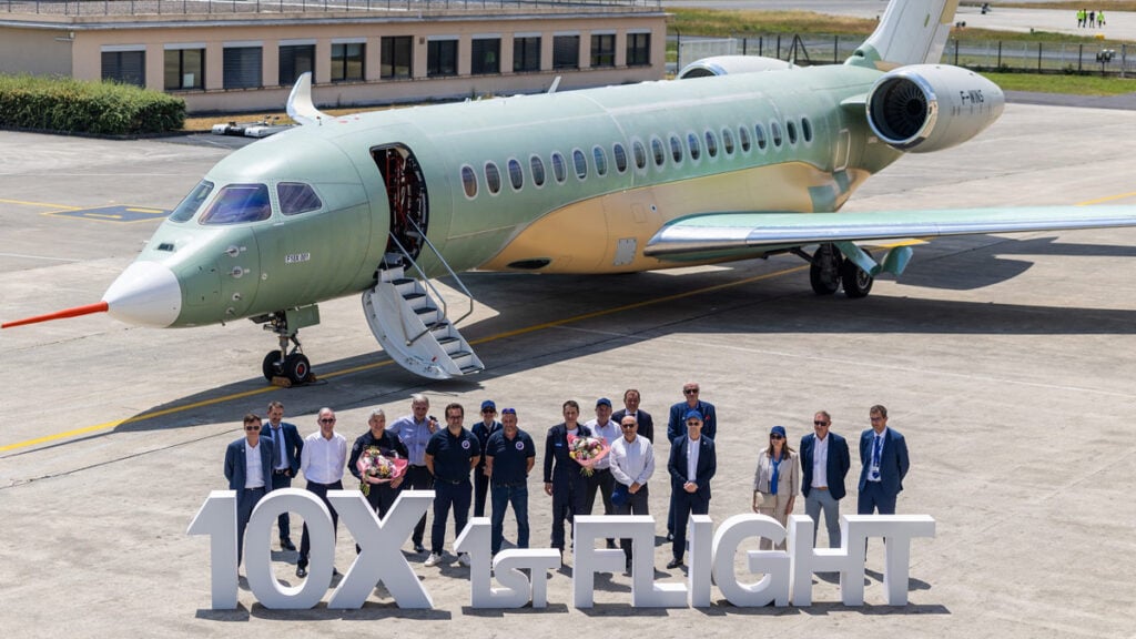 Directivos, ingenieros y pilotos de pruebas de Dassault Aviation posando frente al prototipo del jet ejecutivo Falcon 10X junto a un cartel de '10X 1st Flight' tras el aterrizaje.
