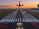 ENAIRE verificación radioayudas drones: Dispositivo no tripulado multirrotor sobrevolando la cabecera de la pista de un aeropuerto durante el atardecer para la calibración de sistemas de navegación.