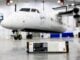 Pratt & Whitney aviación híbrida: Módulo de batería de propulsión de H55 con grado de certificación, presentado en primer plano frente al avión demostrador de RTX en hangar.