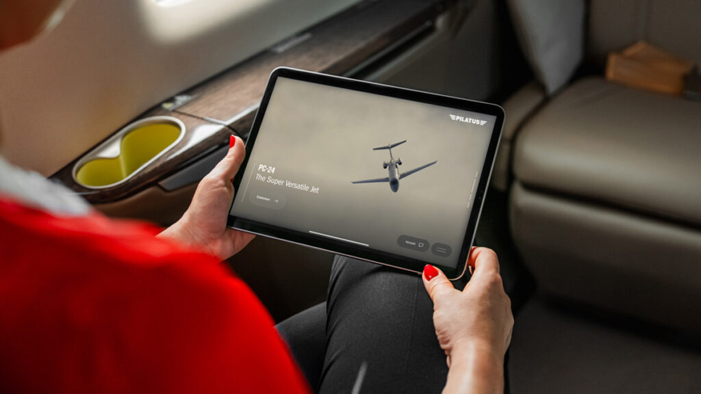 Pasajero utilizando una tablet conectada a la red Gogo Galileo para visualizar el modelo del avión dentro de la cabina de un jet corporativo Pilatus PC-24.