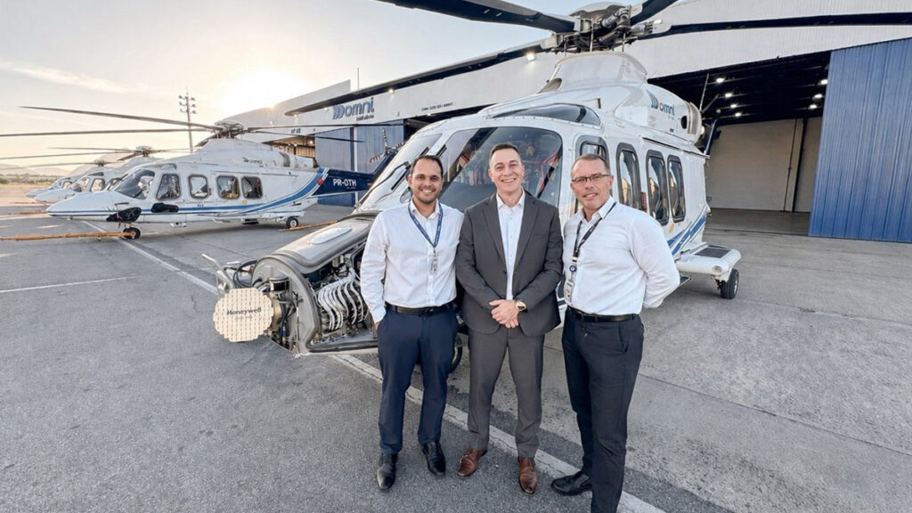 Tres ejecutivos posan frente a un helicóptero AW139 de Omni Táxi Aéreo con el morro abierto mostrando el radar Honeywell RDR-7000