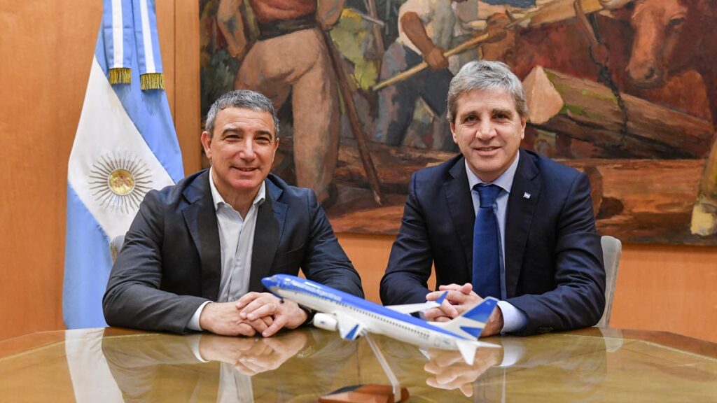 Fabián Lombardo y Luis Caputo reunidos frente a un escritorio con una maqueta de un avión de Aerolíneas Argentinas.